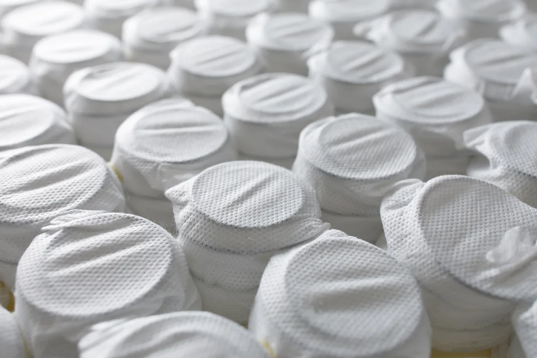 Close-up of individual spring pockets in white nonwoven fabric
