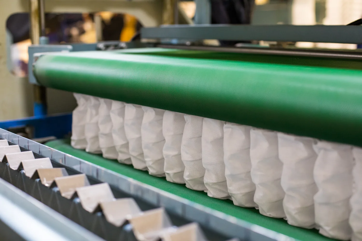 Wrapped pocket springs passing between green production belts